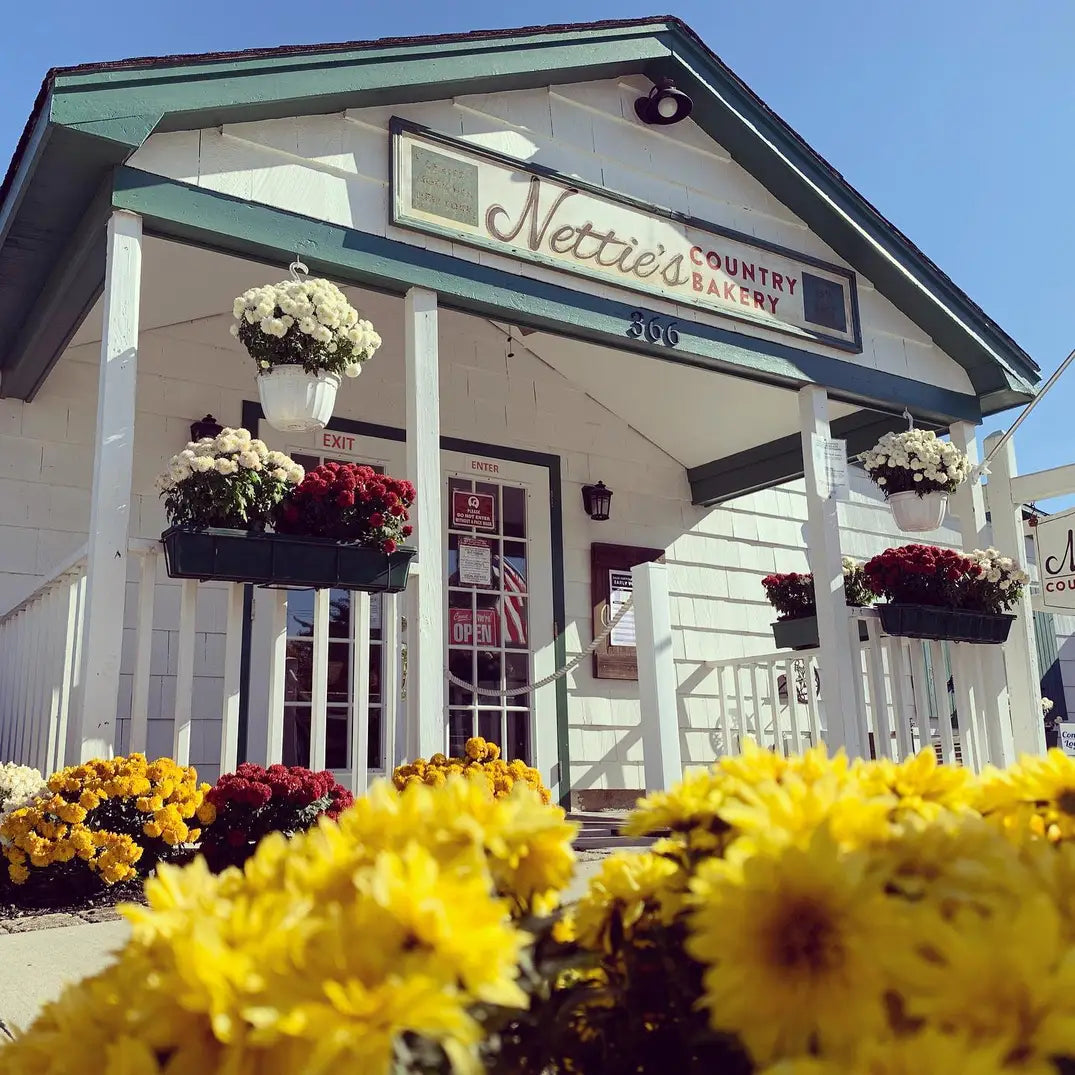 Photo of the exterior entrance area of Nettie's Country Bakery's retail location, with flowers in the foreground.