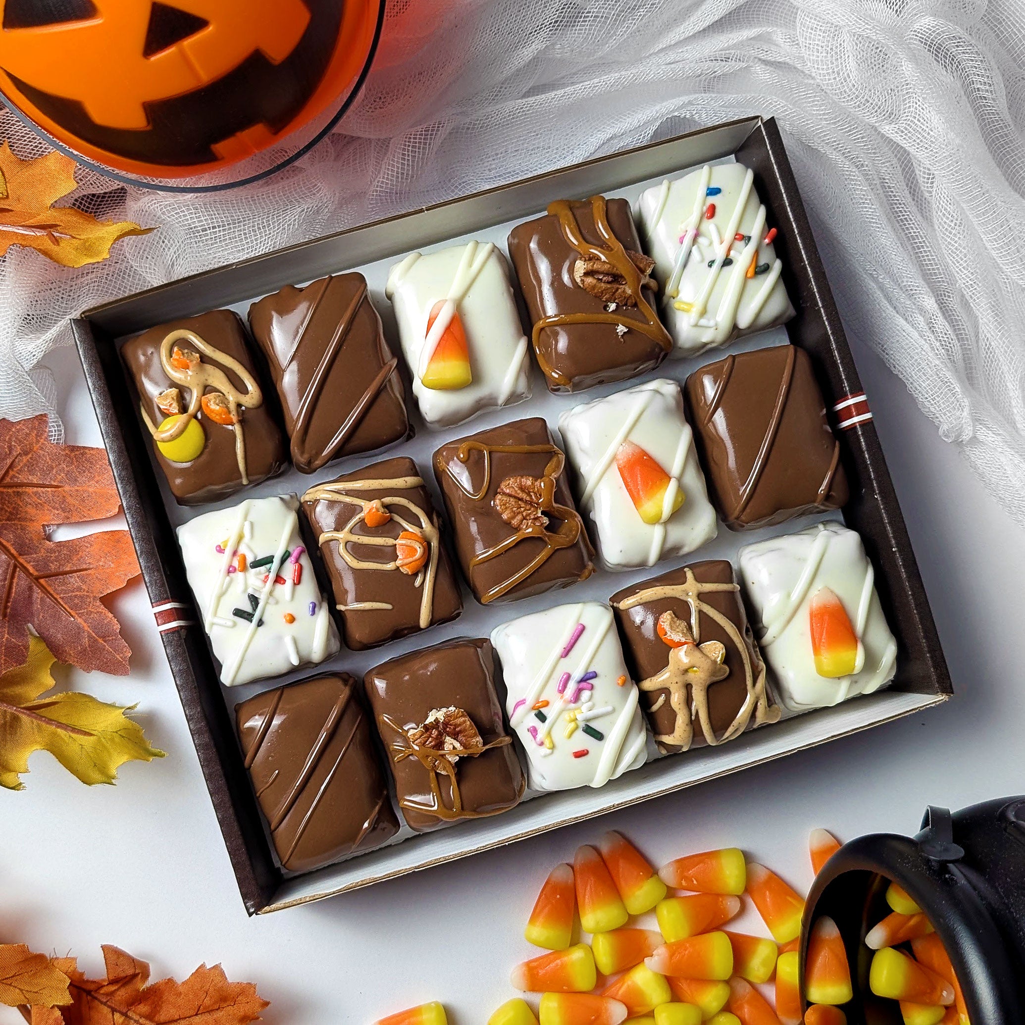 Nettie’s Bakery Halloween Combo gift box featuring chocolate-covered Candy Corn Blondie Bites, Reese’s Pieces Brownie Bites, Caramel Pecan Brownie Bites, Classic Brownie Bites, and White Chocolate Brownie Bites. Gift-ready Halloween treats available for nationwide shipping, pictured with autumn leaves and candy corn.