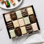 Assorted Nettie’s Bakery cake bites with chocolate and white coatings, pastel drizzle and sprinkles, arranged in a gift box with sliced cake bites on a plate. Available for nationwide shipping.
