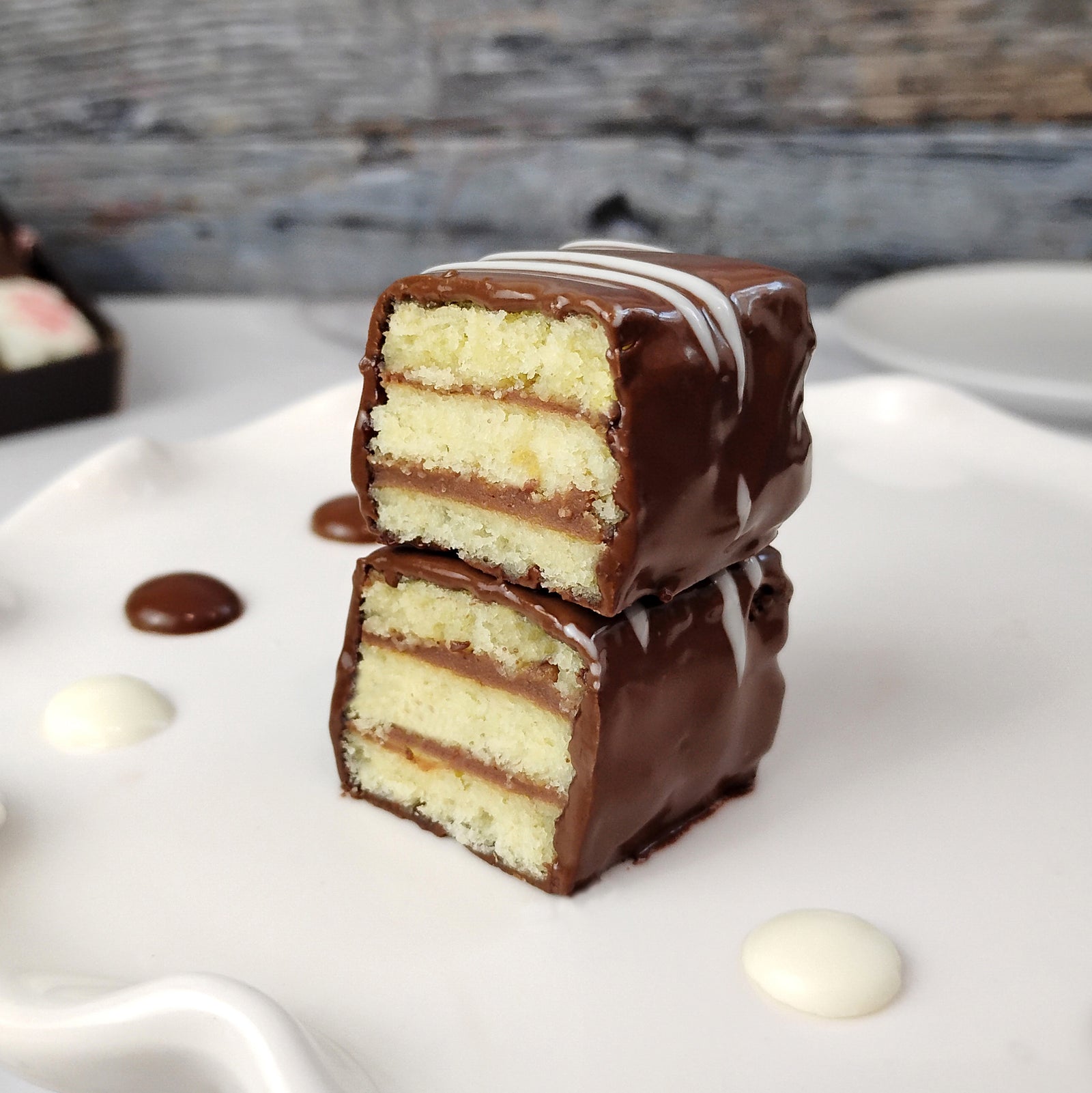 Box of vanilla fudge layer cake bites made with almond cake and chocolate pudding layers, dipped in milk chocolate, packaged for gift delivery and nationwide shipping